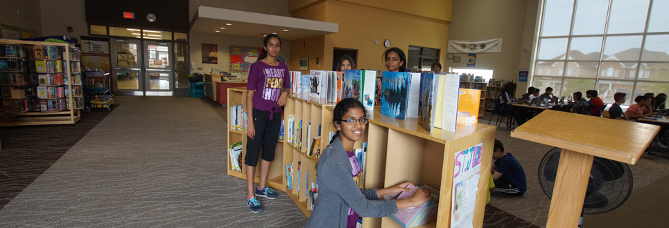 Four female students organizing books in the school's Learning Commons